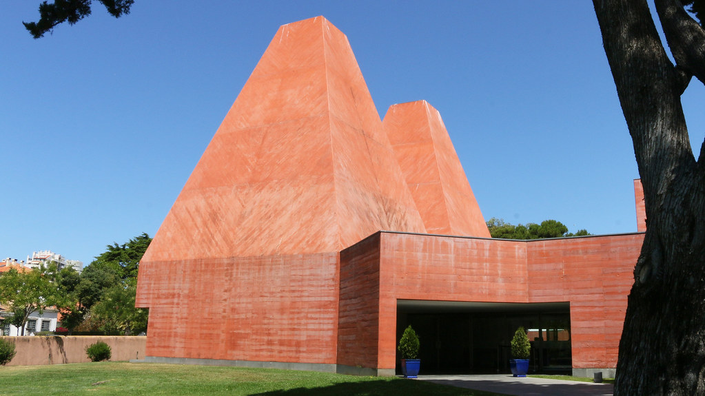 two red brick pyramids adjoining a building surrounded by forest