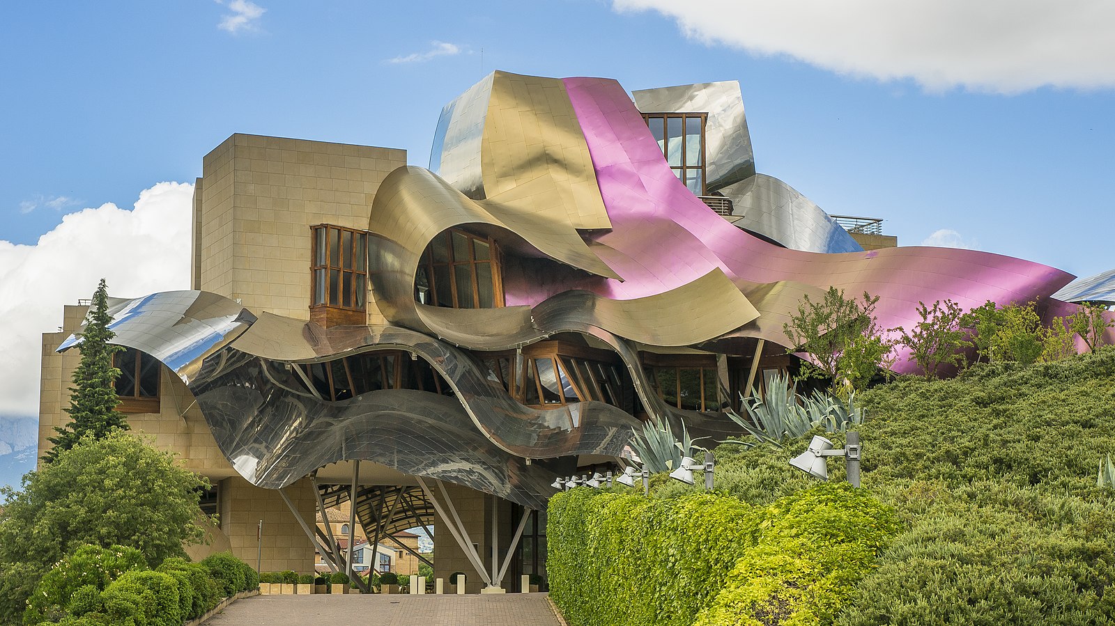A winery with a stone building and a curvy metal roof in purple and gold colors