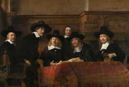 6 men around a table with a red cover, most are standing wearing black and white clothes