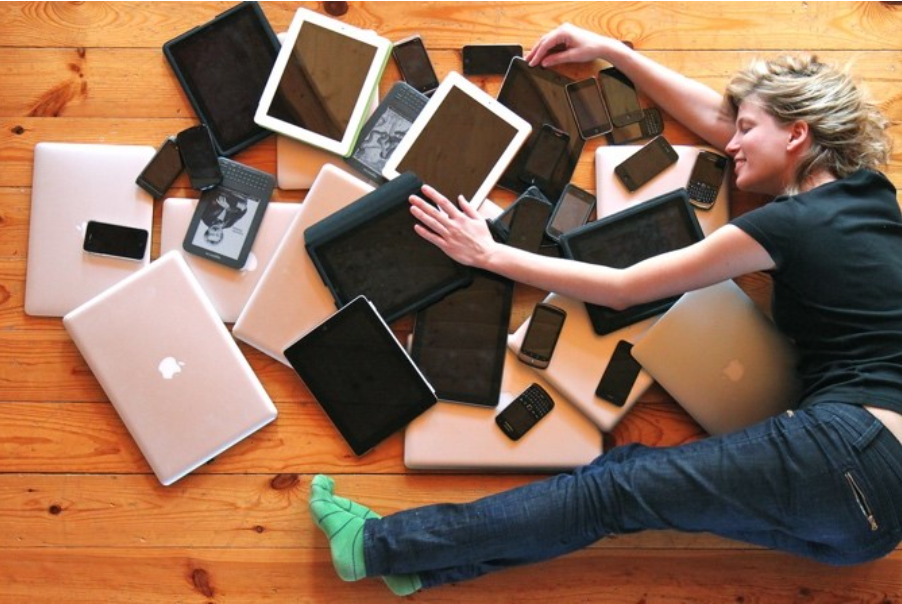 Woman lying down with a bunch of tablettes and computers