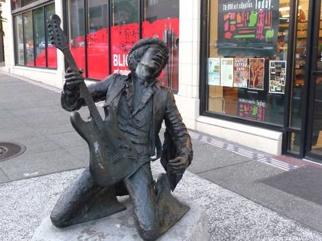 Kneeling stone statue with an electric guitar looking up