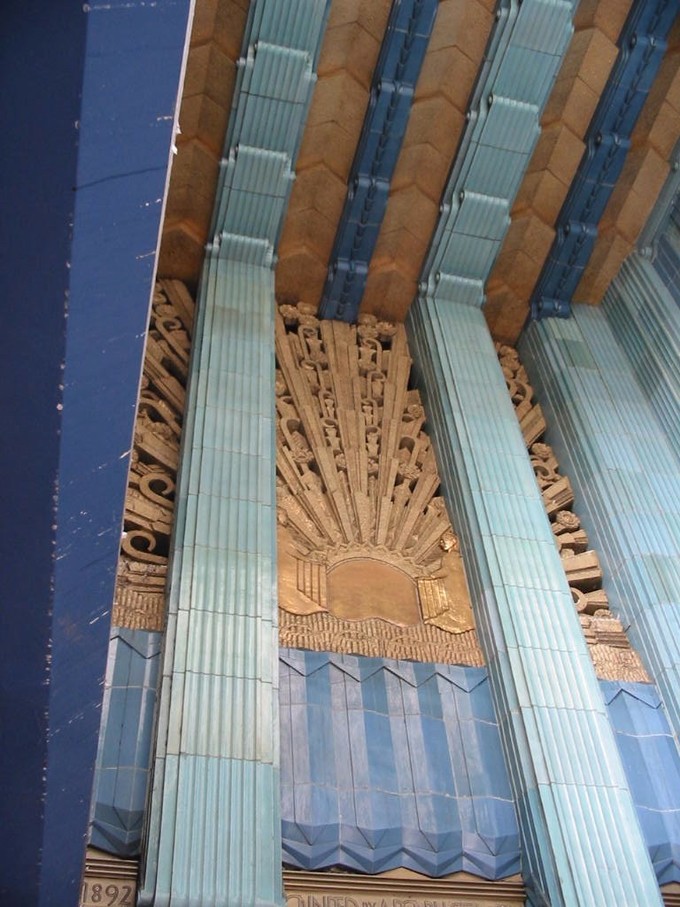 A wall of brown carving with blue trimming and steel-colored pillars