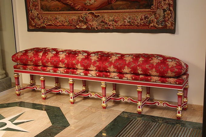 Plush red flowered bench under a picture in a room