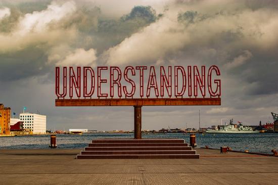 The word "understanding" as a red statue at the edge of a bay.