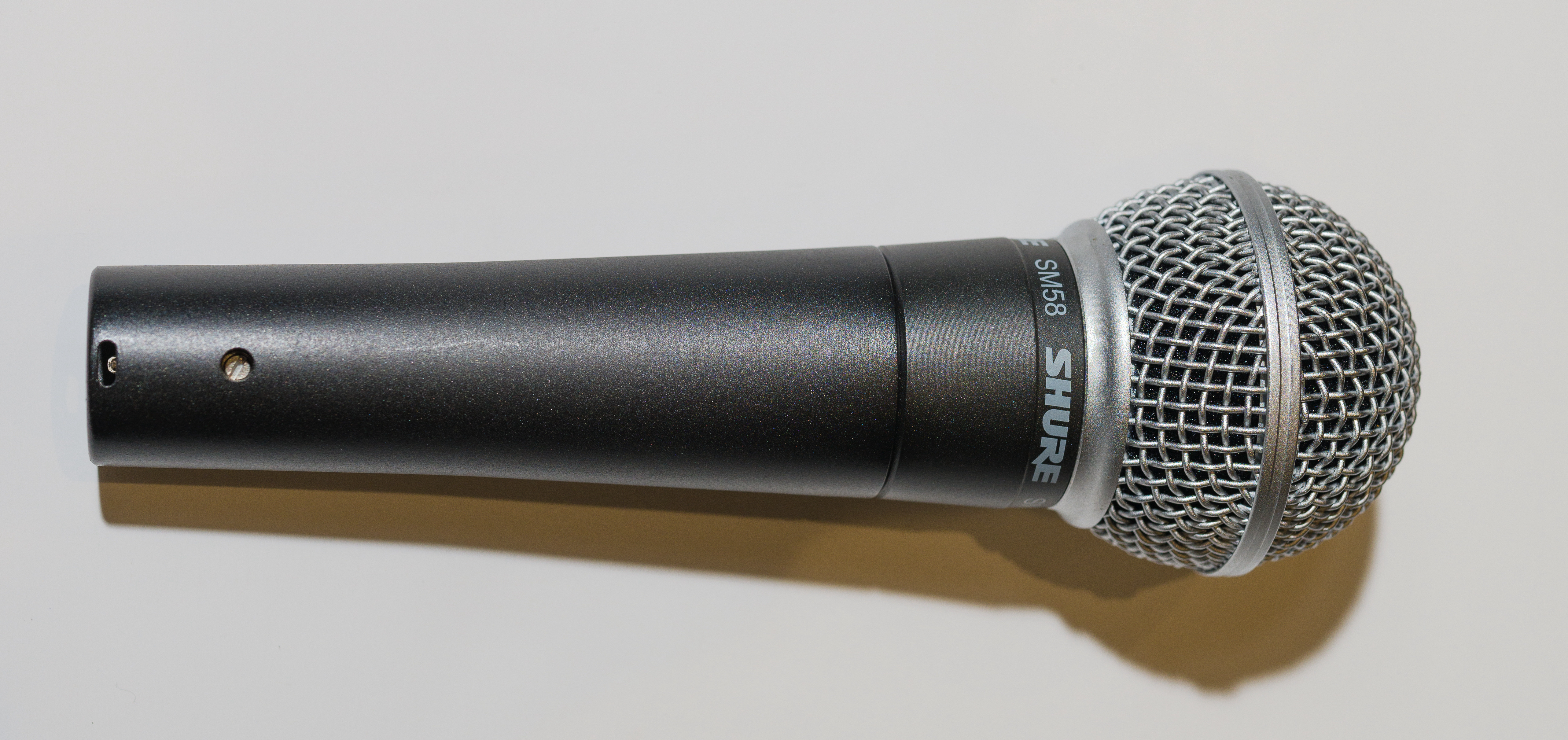 Un micrófono que es cilíndrico en la parte inferior con una bola de malla en la parte superior.
