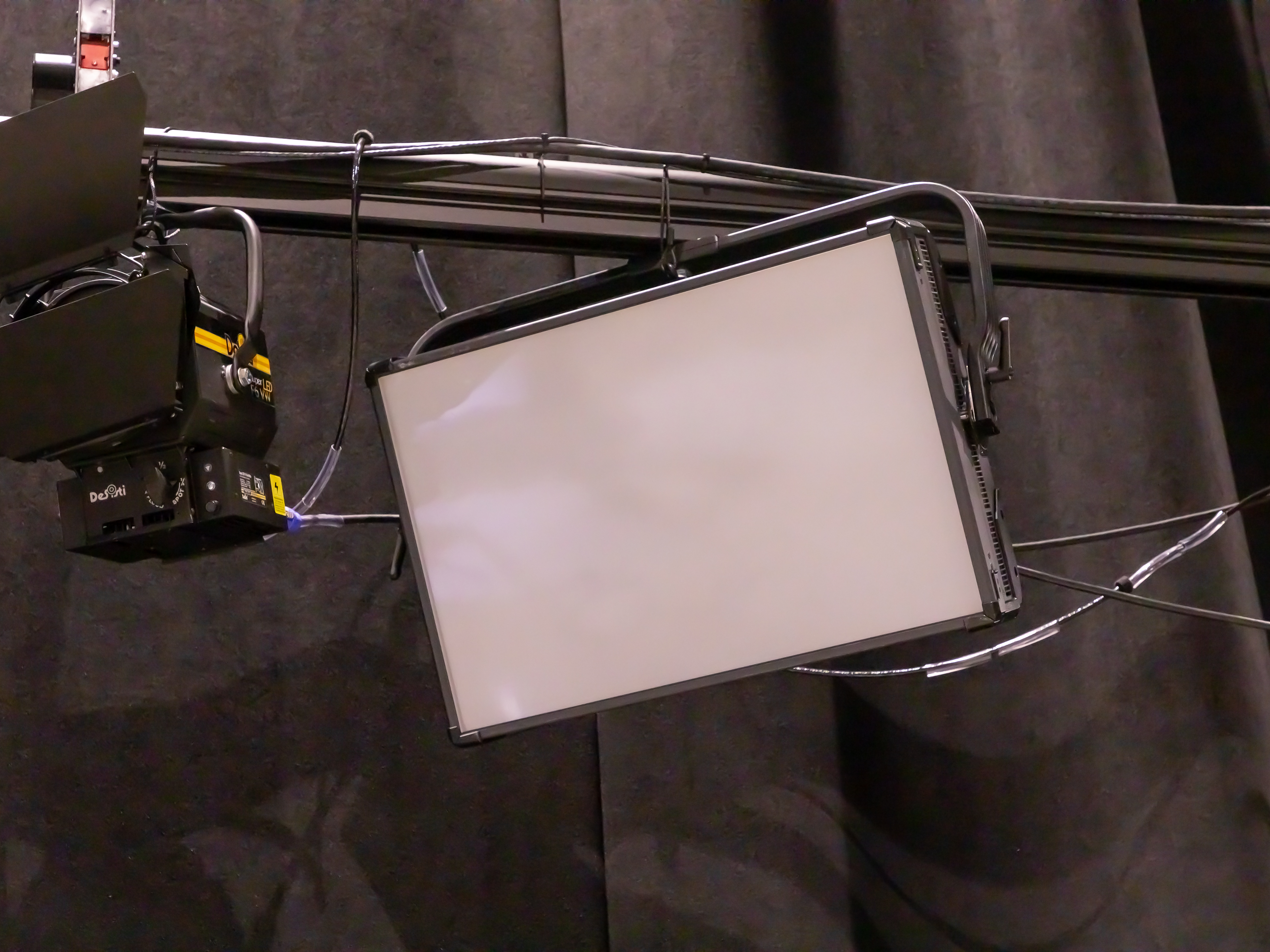 A panel light hanging from a baton. It is rectangular with a white frosted covering.