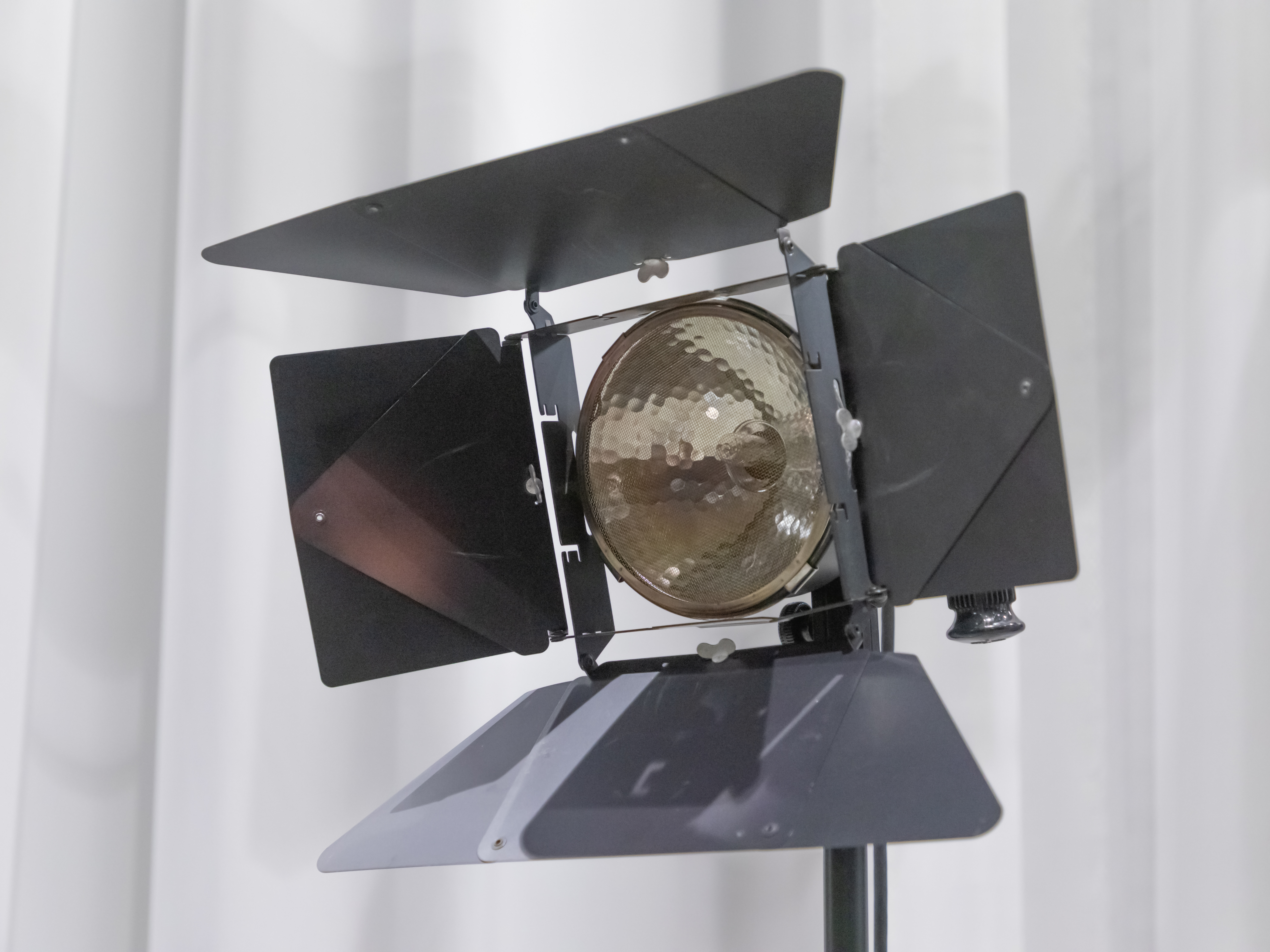 A Fresnel light with barn doors, which are four metal flaps on top, bottom, left, and right. 