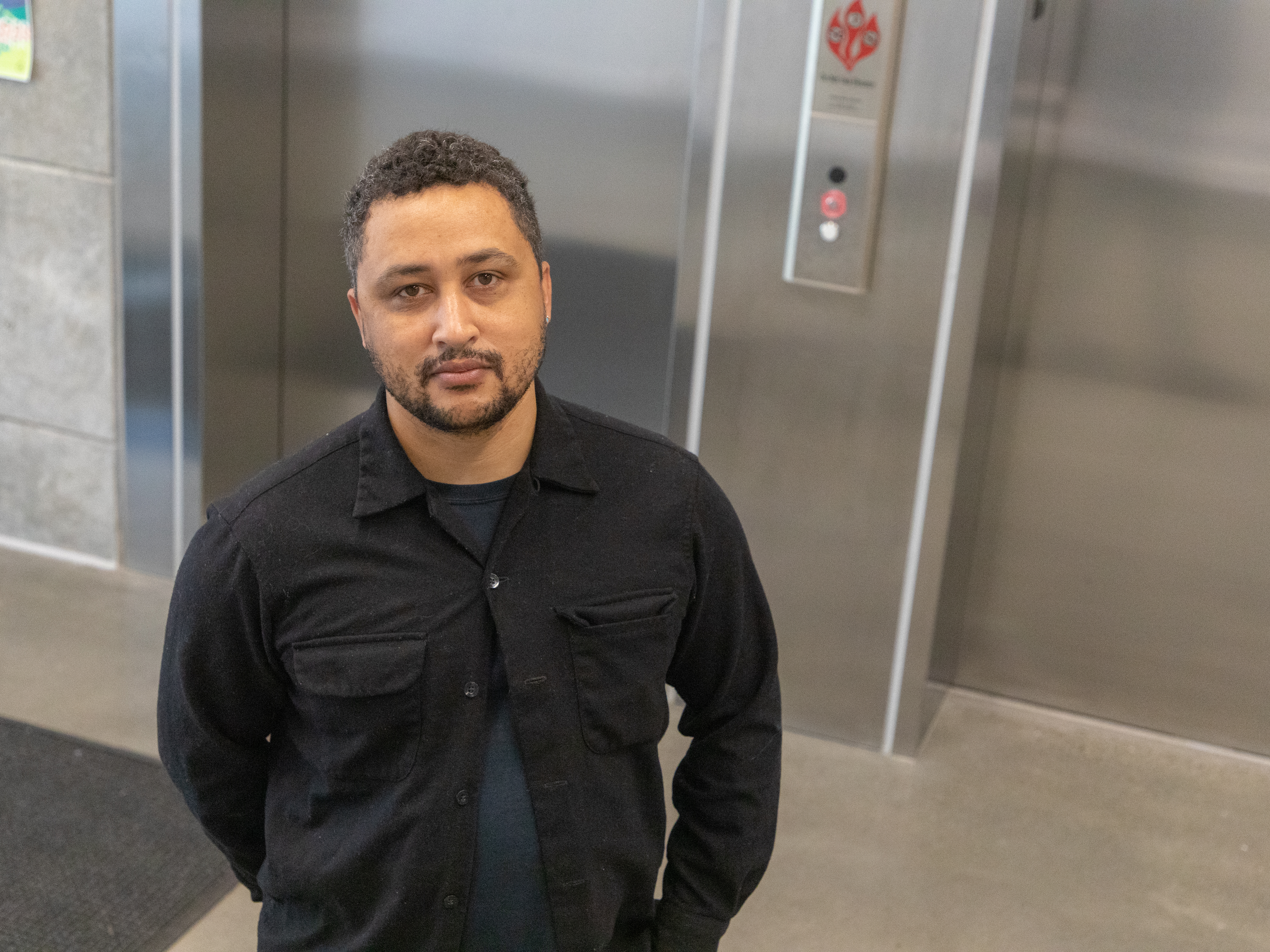 A man standing in front of an elevator. We are looking down on him as if we were two feet taller.