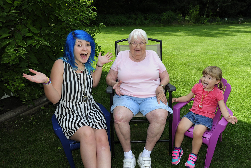 Grandmother and granddaughter smiling while sitting in a park