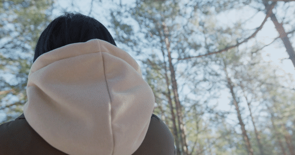The camera moves around a woman from her back to her front in the forest.