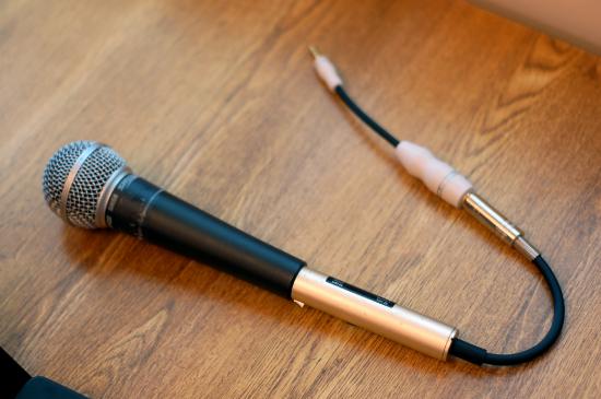 A handheld microphone with an XLR to Phone plug wire attached with a phone to mini plug adapter.  