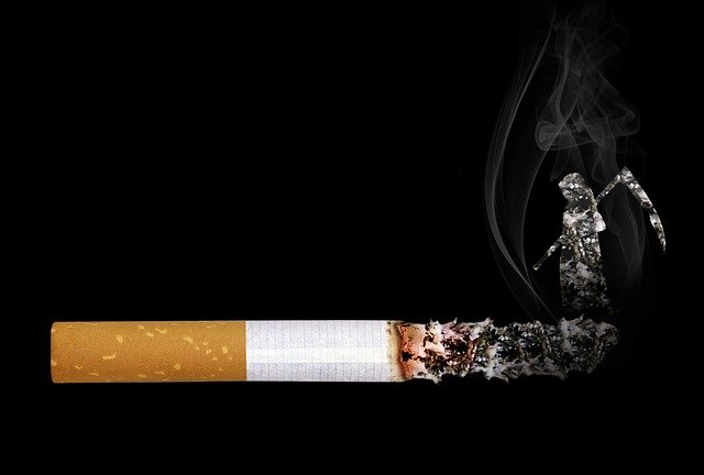 Une cigarette surdimensionnée sur fond noir avec de longues cendres, la faucheuse émergeant de la cendre avec la fumée, face au mégot de la cigarette