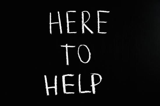 The words "Here to help" on a chalkboard