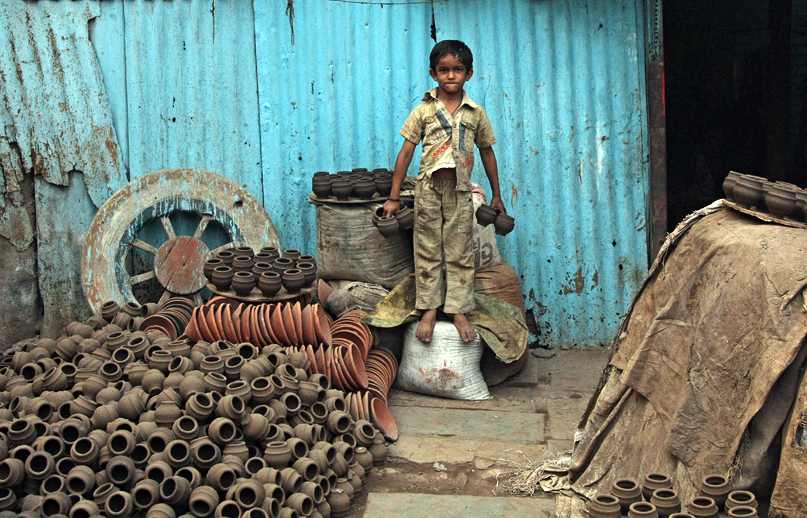 Un niño se para en el patio de un alfarero, sosteniendo tazas de barro tradicionales (foto: Meena Kadri, CC BY-NC-ND 2.0)
