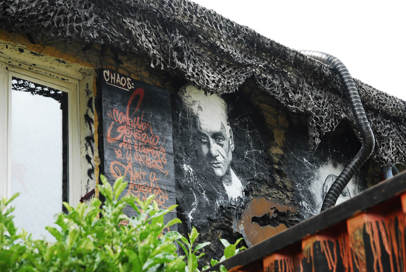 Peinture de Jacques Derrida sur un bâtiment, avec d'autres graffitis.