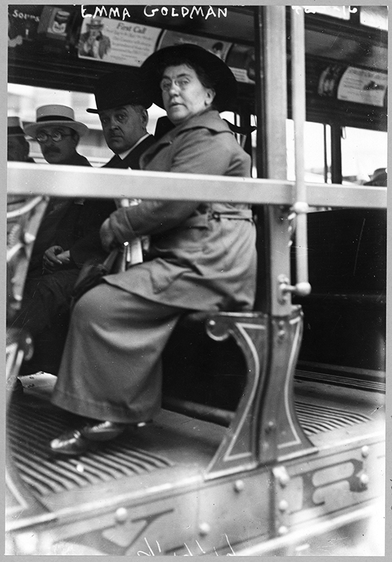 一张照片显示艾玛·戈德曼坐在街车的长凳上。 两个男人坐在她旁边的长凳上。