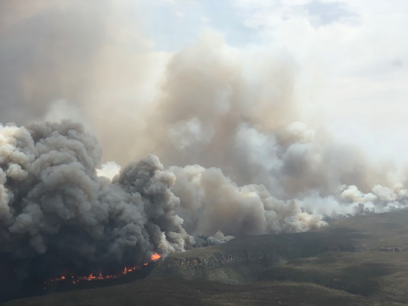 Далеких вид на краєвид з величезними хмарами диму, що піднімається від пожеж, палаючих на землі.