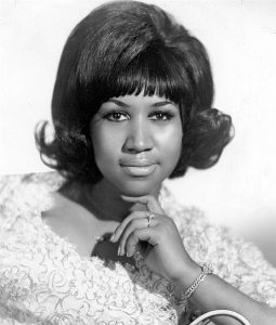 Black and white photographic image of Aretha Franklin in a floral top.