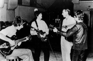 Black and white photographic image of the Beatles practicing.