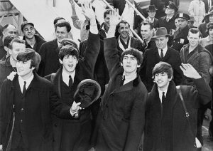 Black and white photographic image of the Beatles arriving at JFK airport.