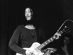 A black and white photo of Peter Green playing the guitar.