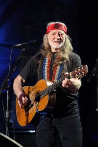Color photograph of Willie Nelson playing guitar on stage (2009)