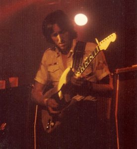 Colored photo of AH playing the guitar live - 1975