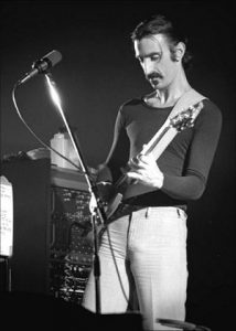 Black and white photo of Frank Zappa playing guitar live