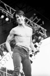 Black and white photo of Iggy Pop performing live shirtless
