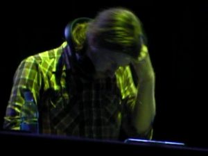 Member of Aphex Twin with headphones in green lighting.